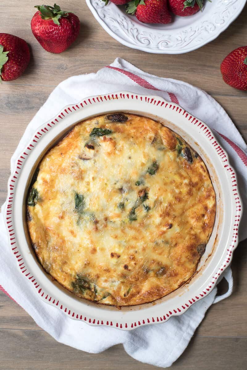 Spinach Mushroom and Feta Crustless Quiche in a white dish on a kitchen cloth.