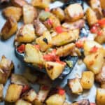 Breakfast potatoes with peppers and onions on a baking sheet.