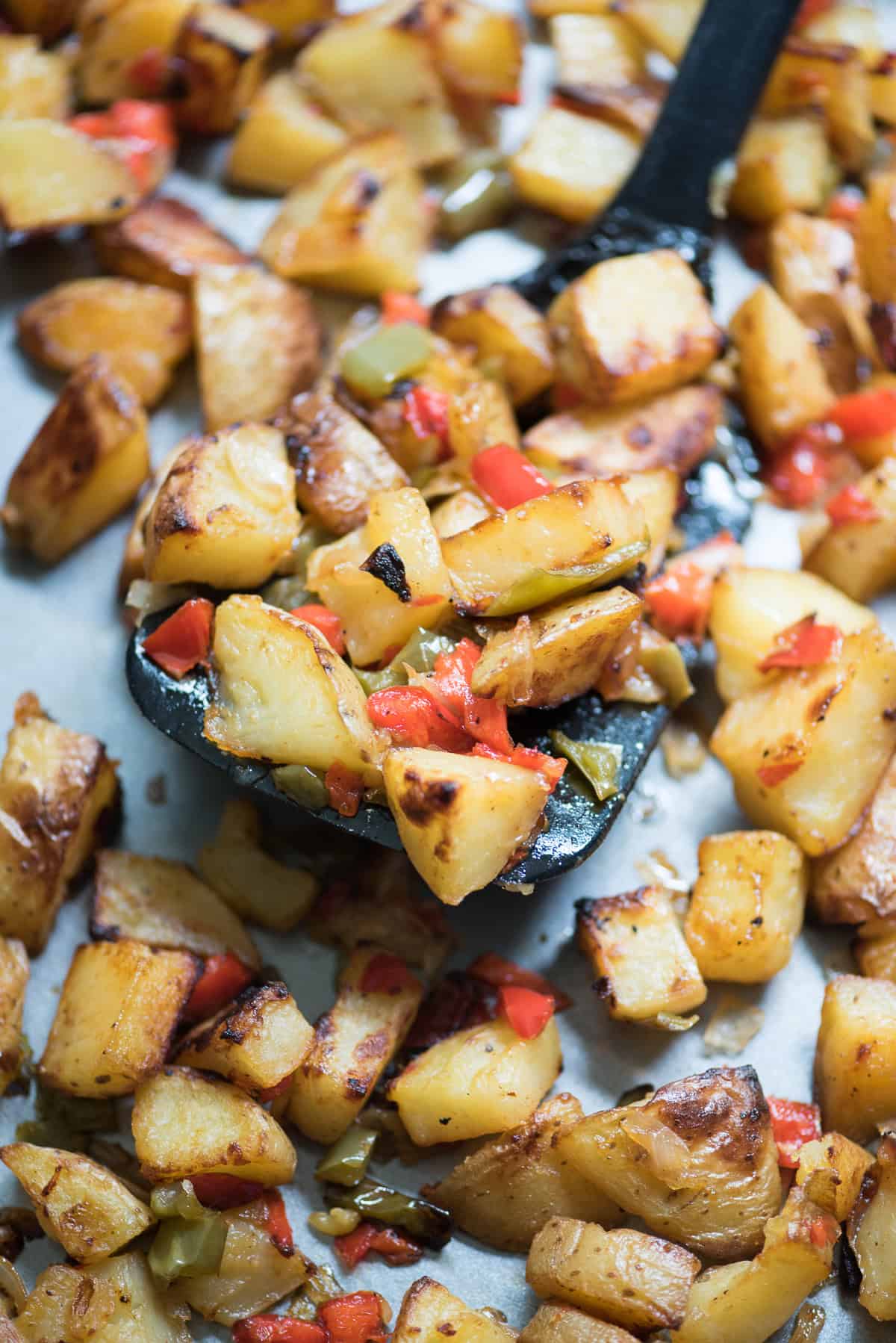 Breakfast potatoes with peppers and onions on a baking sheet.