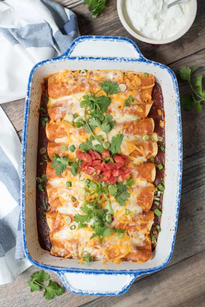 Easy Slow Cooker Chicken Enchiladas in a white casserole dish shot from over the top.