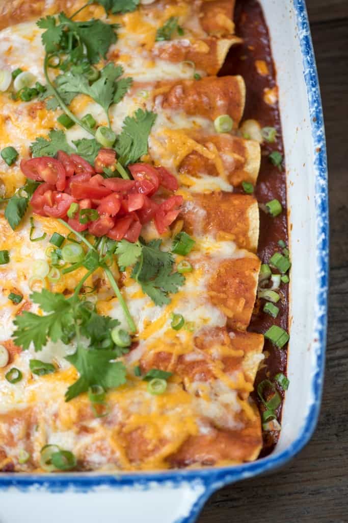 A close up image of the cooked enchiladas topped with cilantro and tomatoes.