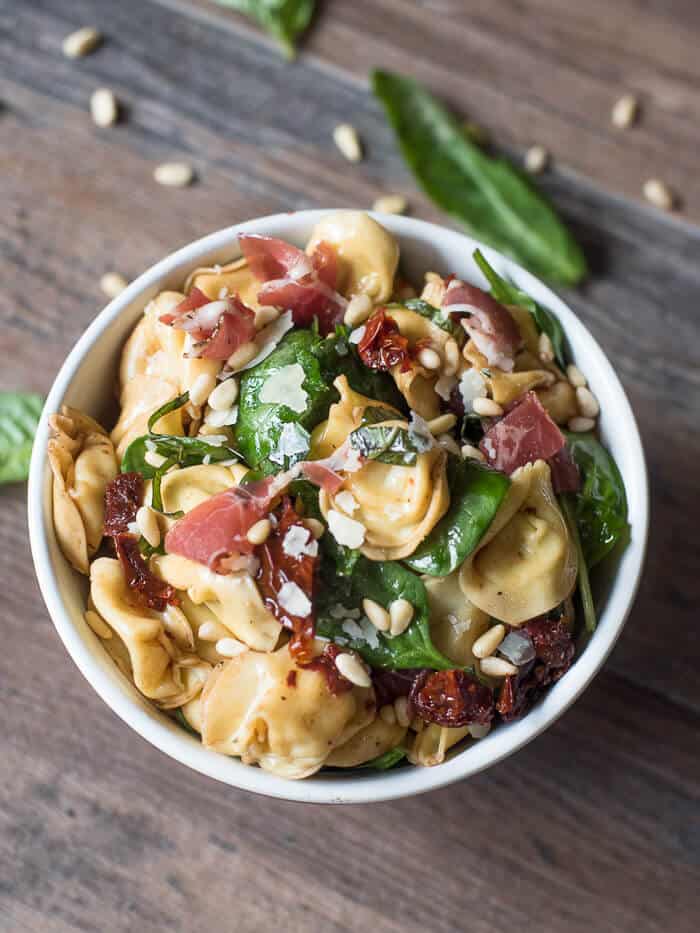 Italian Tortellini Salad in a small white bowl on a board.