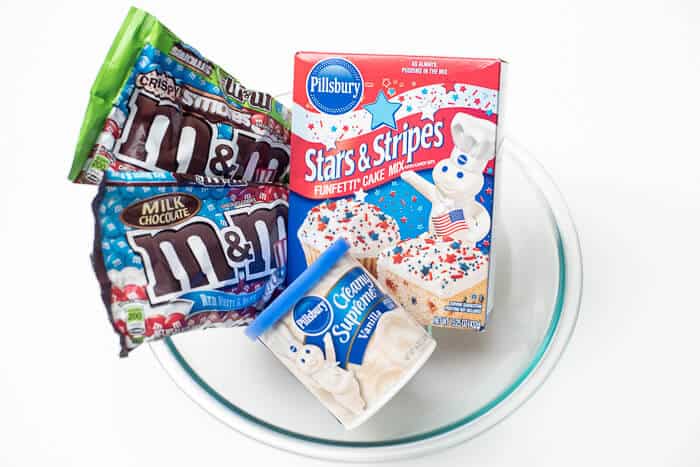 Two bags of M&M's, a box of Pillsbury Stars & Stripes Funfetti Cake Mix, and and container of Pillsbury frosting.