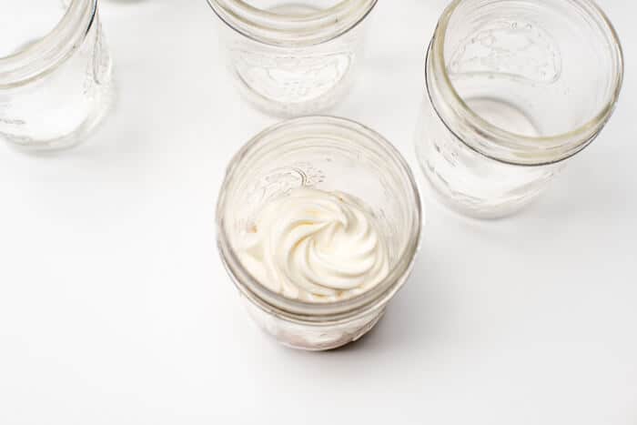 A swirl of vanilla frosting on top of the cupcake half in the mason jar.
