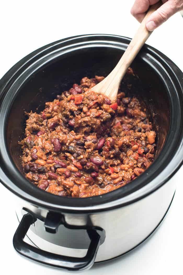 Slow-Cooker 3-Bean Cowboy Beans being scooped up with a wooden spoon.