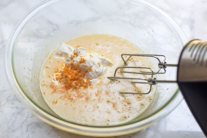 Sour cream and orange zest is added to the mixing bowl.