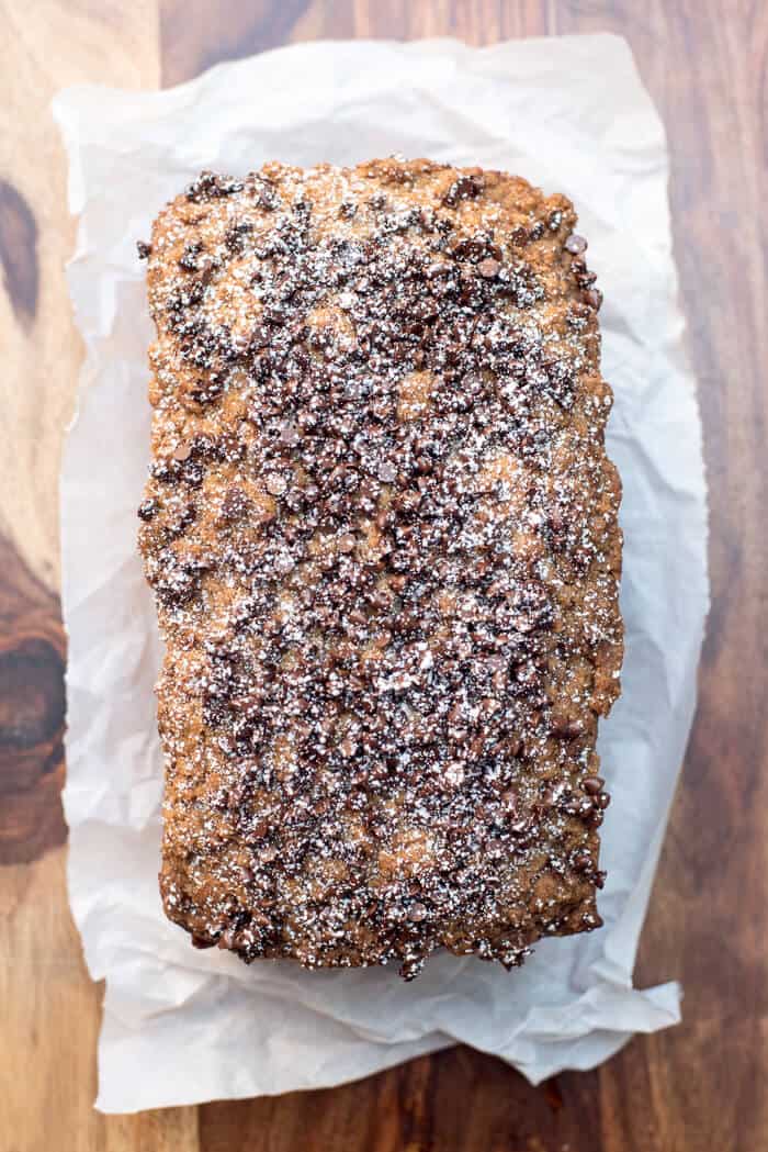 An over the top image of a cake sprinkled with powdered sugar on a wood cutting board.