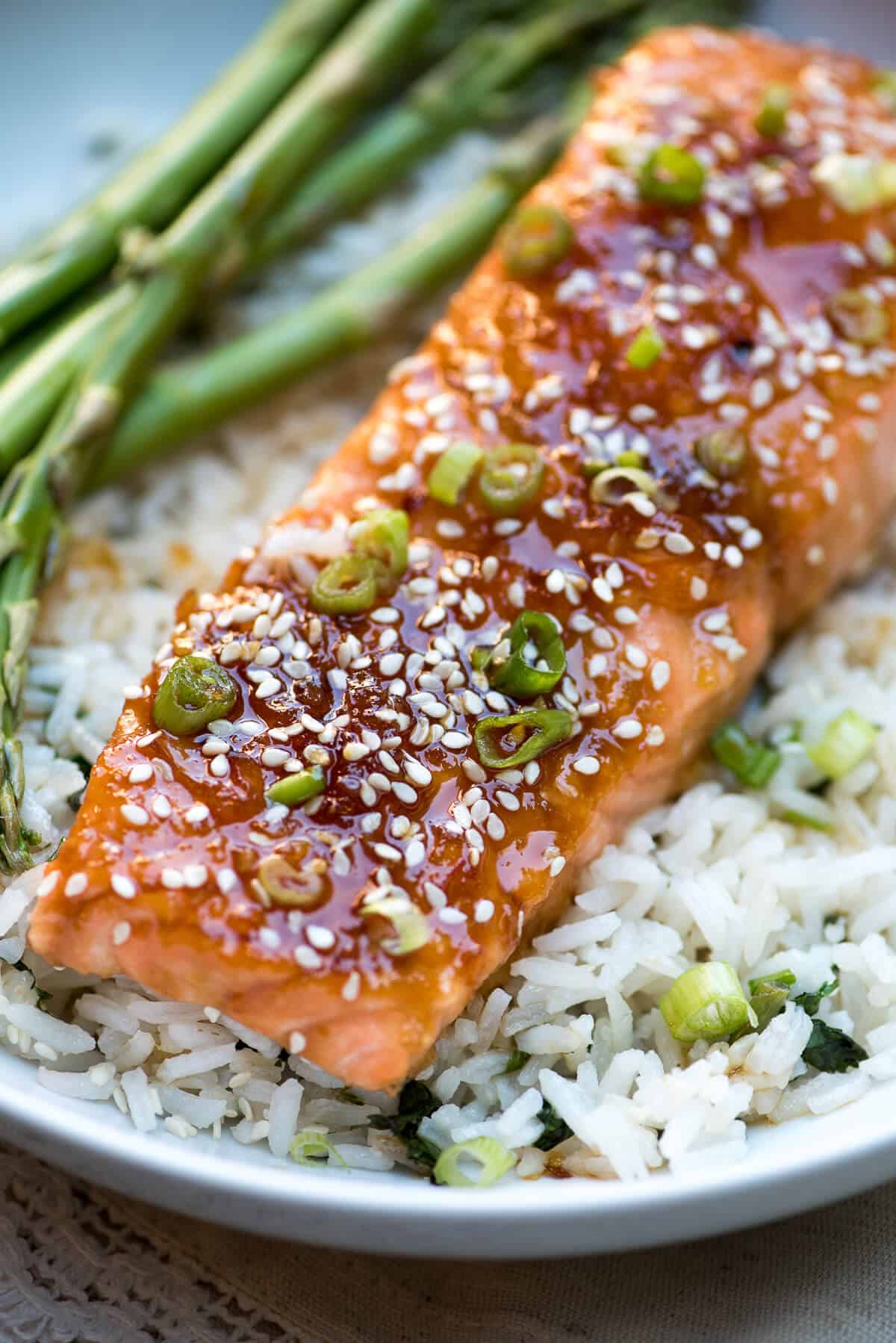 A close up of Asian glazed salmon with sesame seeds on a bed of rice.