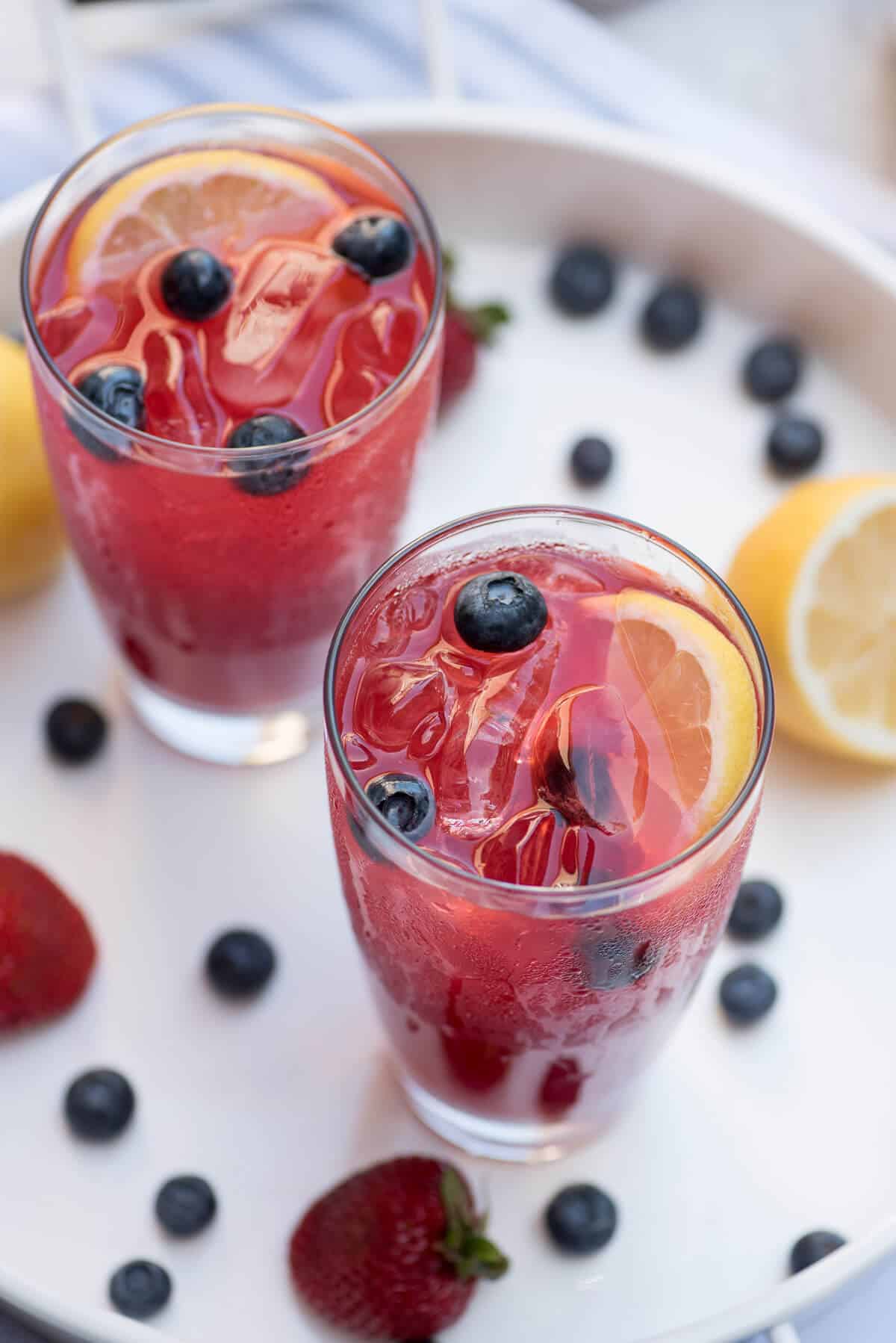 An overhead shot of two glasses of Berry Lemonade with lemons slices and blueberries.