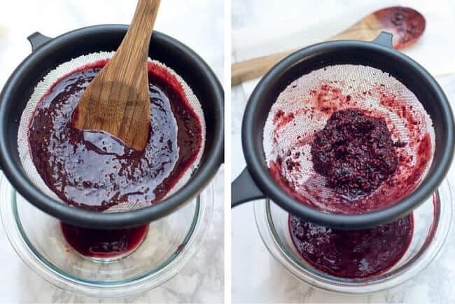 Berry puree being strained through a wire mesh colander.