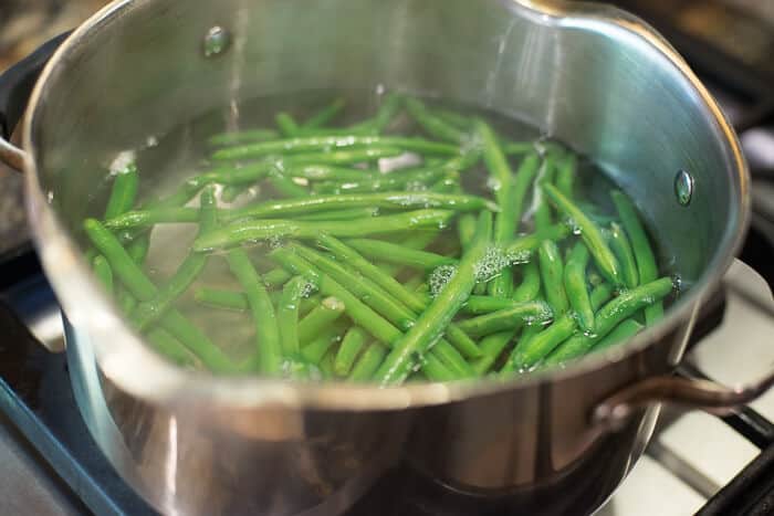 Green beans cooking in a pot of water on the stove.