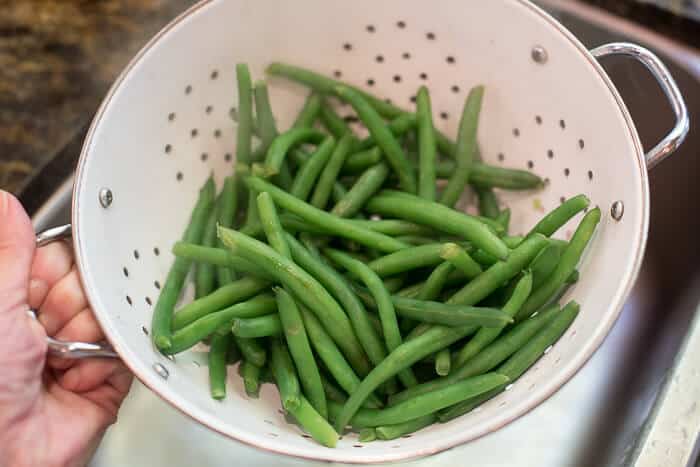 Green beans draining in a white colander.