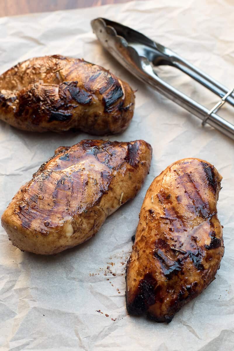 Whole pieces of grilled chicken on parchment paper.
