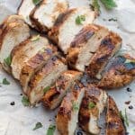 Slices of grilled chicken on parchment paper.