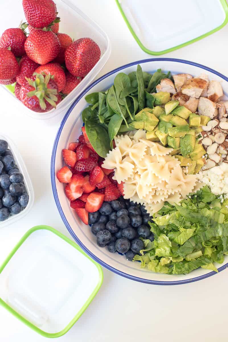 Pasta, berries, spinach, avocado, and chicken in a bowl.