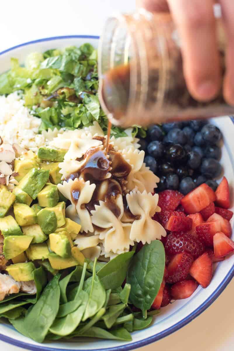 Balsamic dressing pouring on to Chicken Berry Pasta Salad.