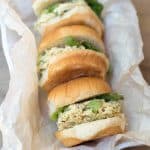 Curry chicken salad on small buns on parchment paper.