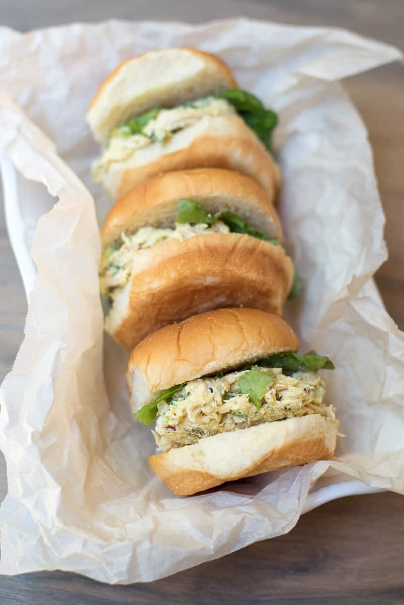 Sandwiches on small buns in a parchment paper lined dish.