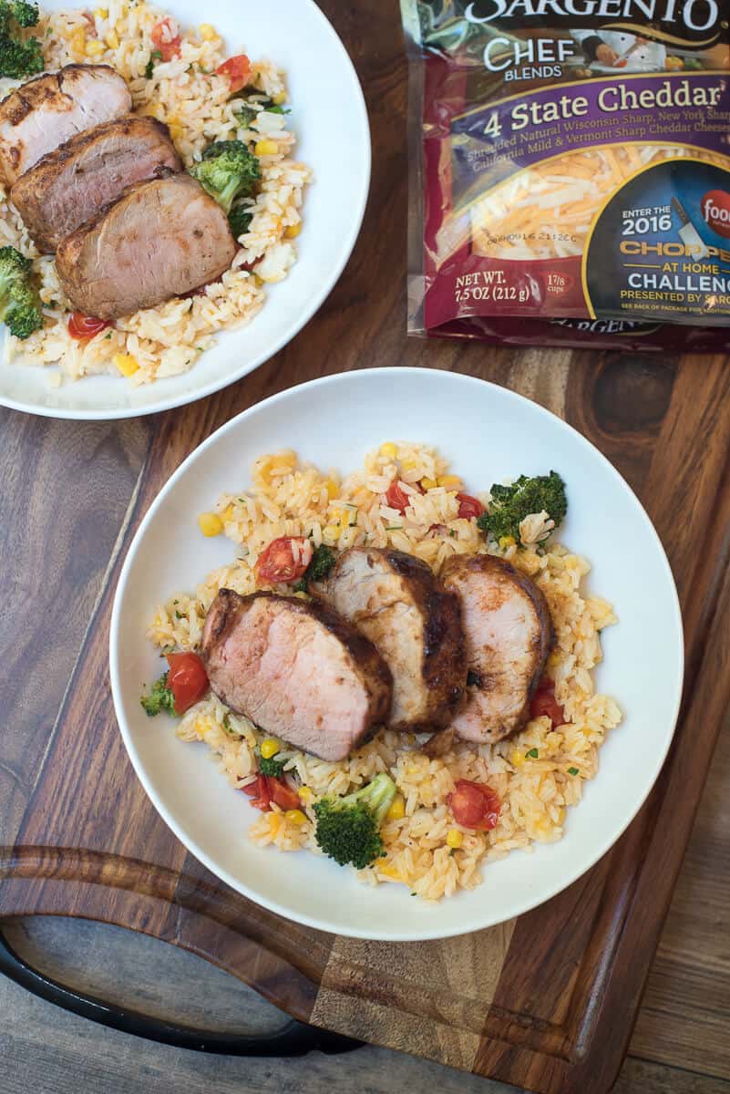 Grilled Pork Tenderloin with Cheesy Vegetable Rice in two white bowls next to a package of shredded cheese.