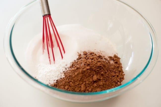 The dry ingredients in a glass mixing bowl with a whisk.