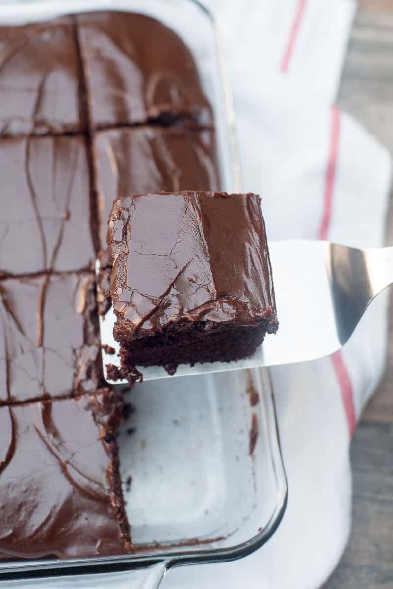 A slice of chocolate cake being lifted from the baking dish on a spatula.