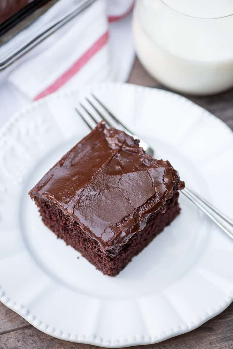 A slice of One Bowl Chocolate Cake on a white serving plate with a fork.