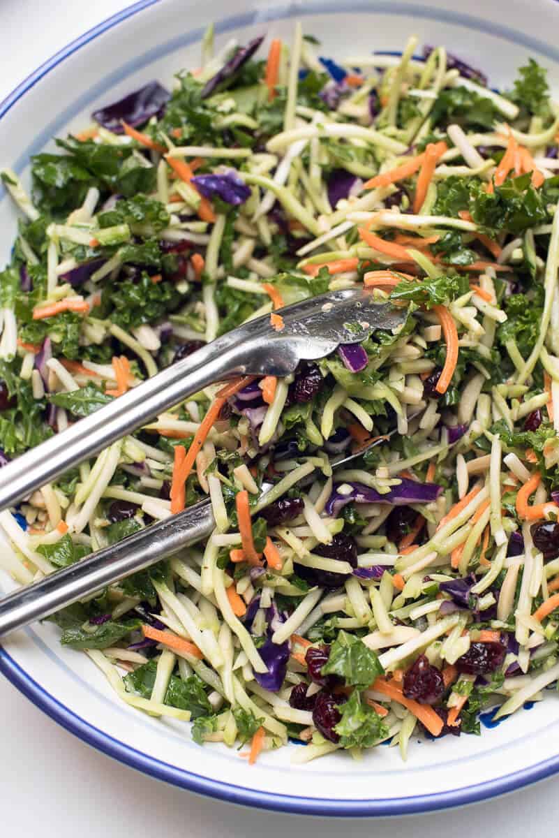 A close up image of 5 Minute Broccoli Kale Slaw with metal tongs.