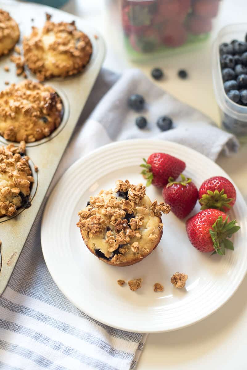 A Blueberry Granola Crunch Muffin on  white plate with strawberries.