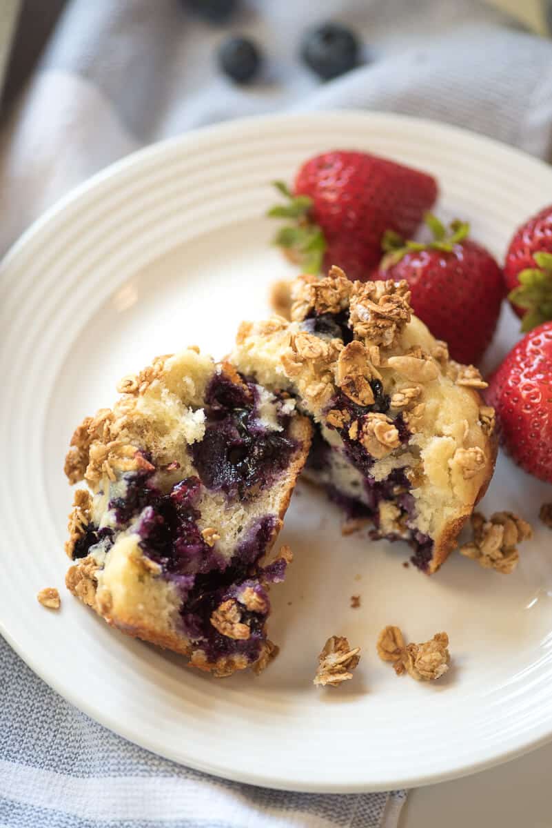 A muffin is broken in half on a white plate.