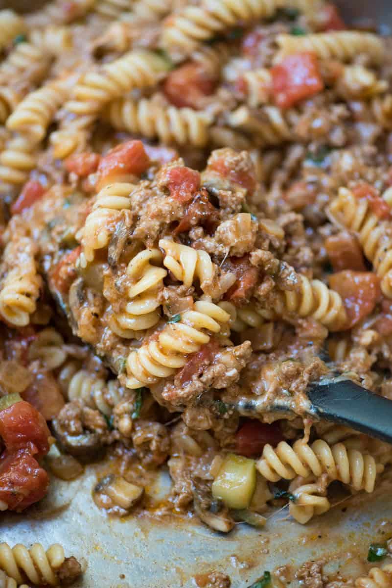 A closeup of cheesy pasta with beef in a skillet.