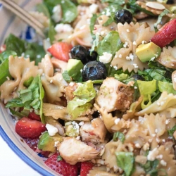 A close up pasta salad with chicken and berries.