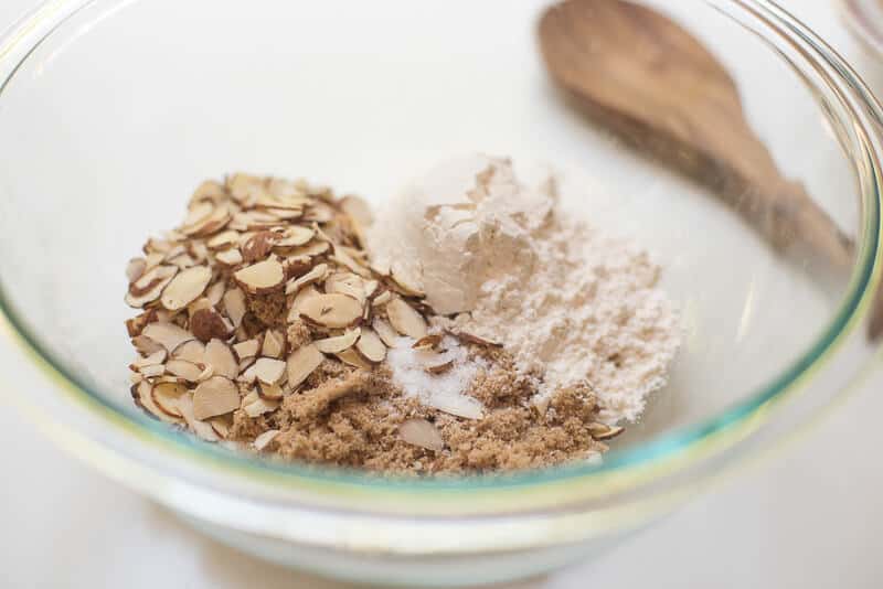 Flour, brown sugar, and sliced almonds in a glass bowl.