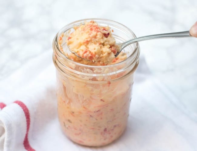 A spoon scooping up some Giardiniera Sandwich Spread from a mason jar.