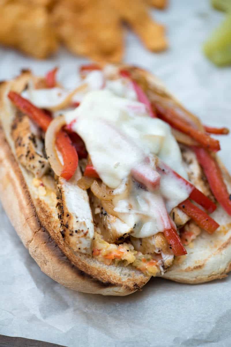 A closeup of a sub with peppers and onions and melted provolone cheese.