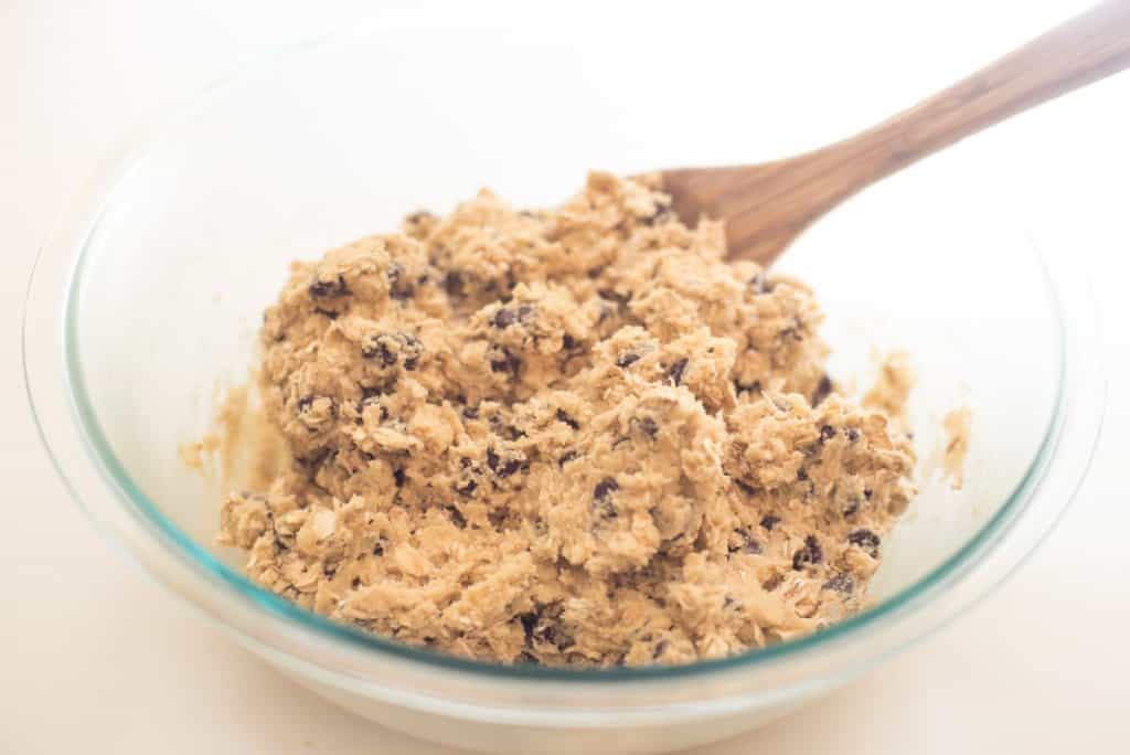 The cookie dough is combined with a wooden spoon.