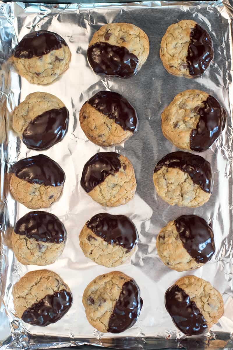 A foil lined baking sheet filled with chocolate dipped oatmeal cookies.