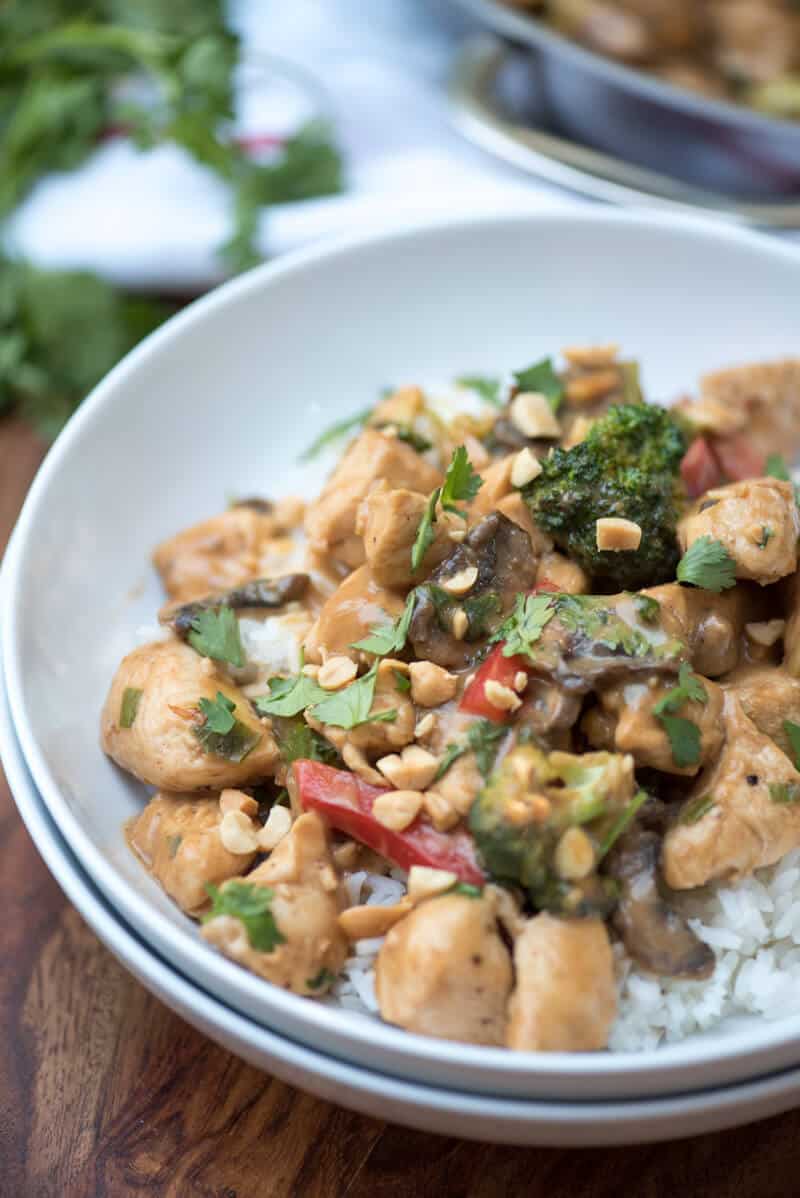 A close up of the peanut chicken stir fry in a white bowl.