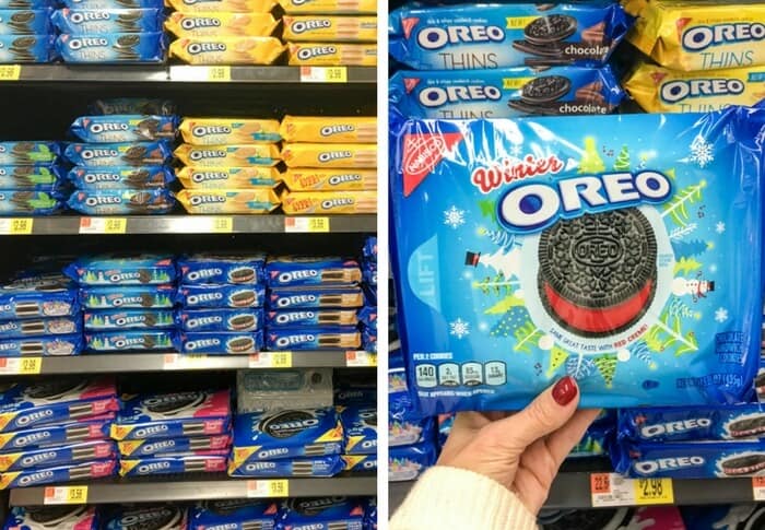 A hand holds a package of Winter Oreos in front of grocery store shelves at Walmart.