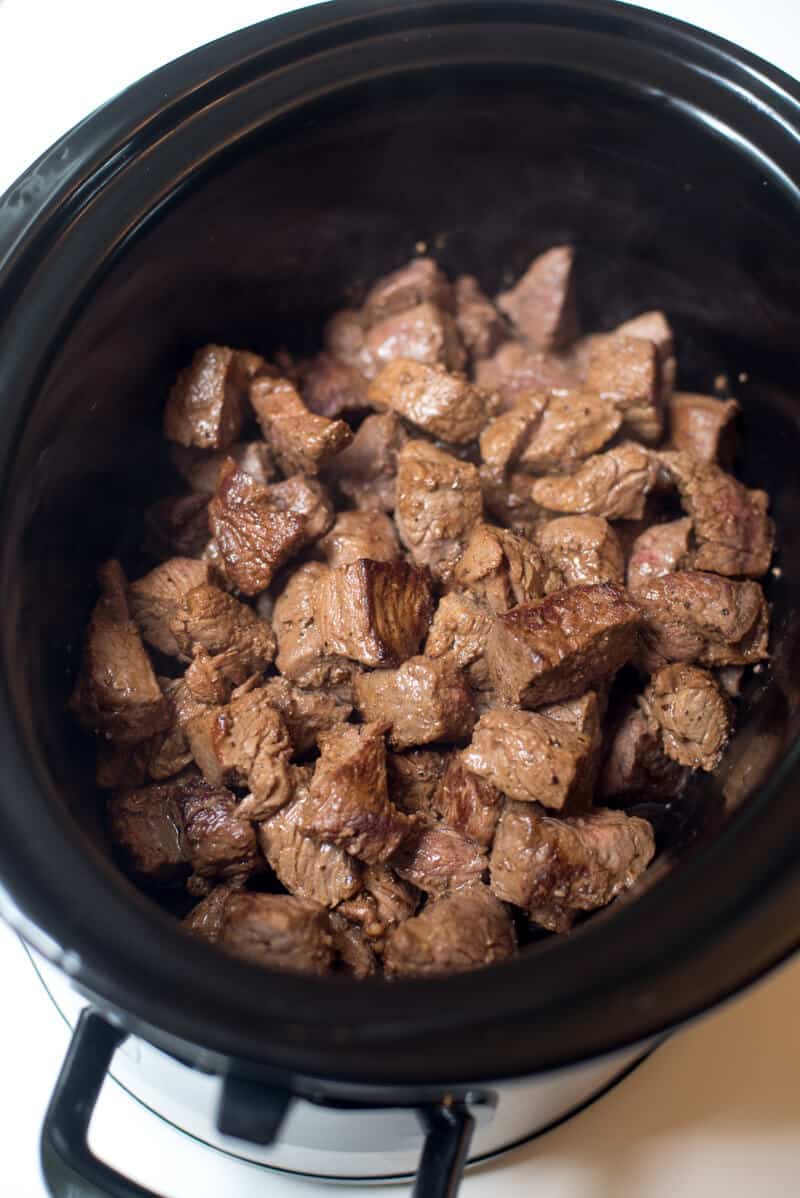 An in process shot of the beef tips in a slow cooker.