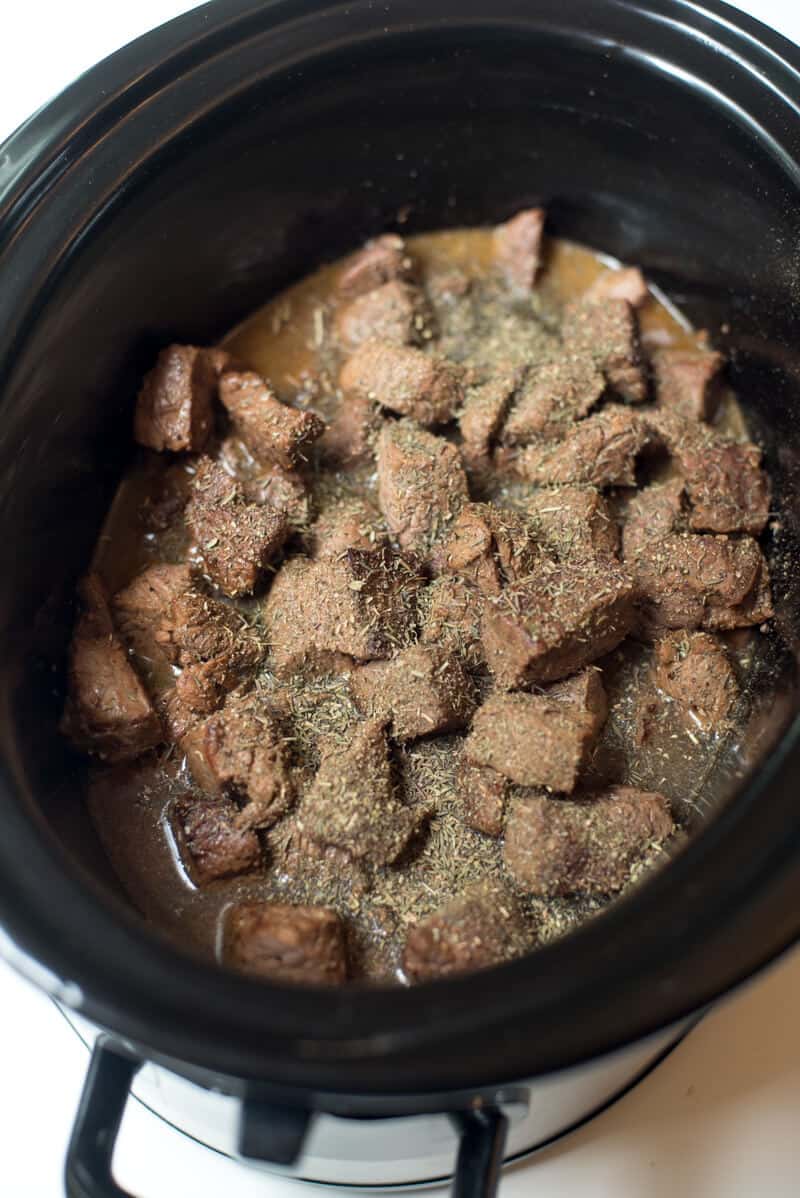 An in process shot of the seasoning sprinkled over the beef tips in the slow cooker.