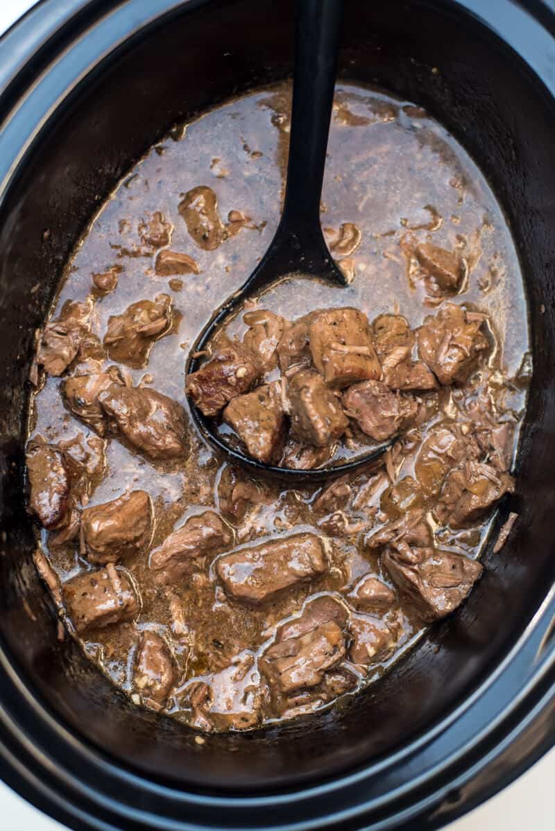 A ladle spooning up some of the finished Slow Cooker Beef Tips with Gravy out of the slow cooker.