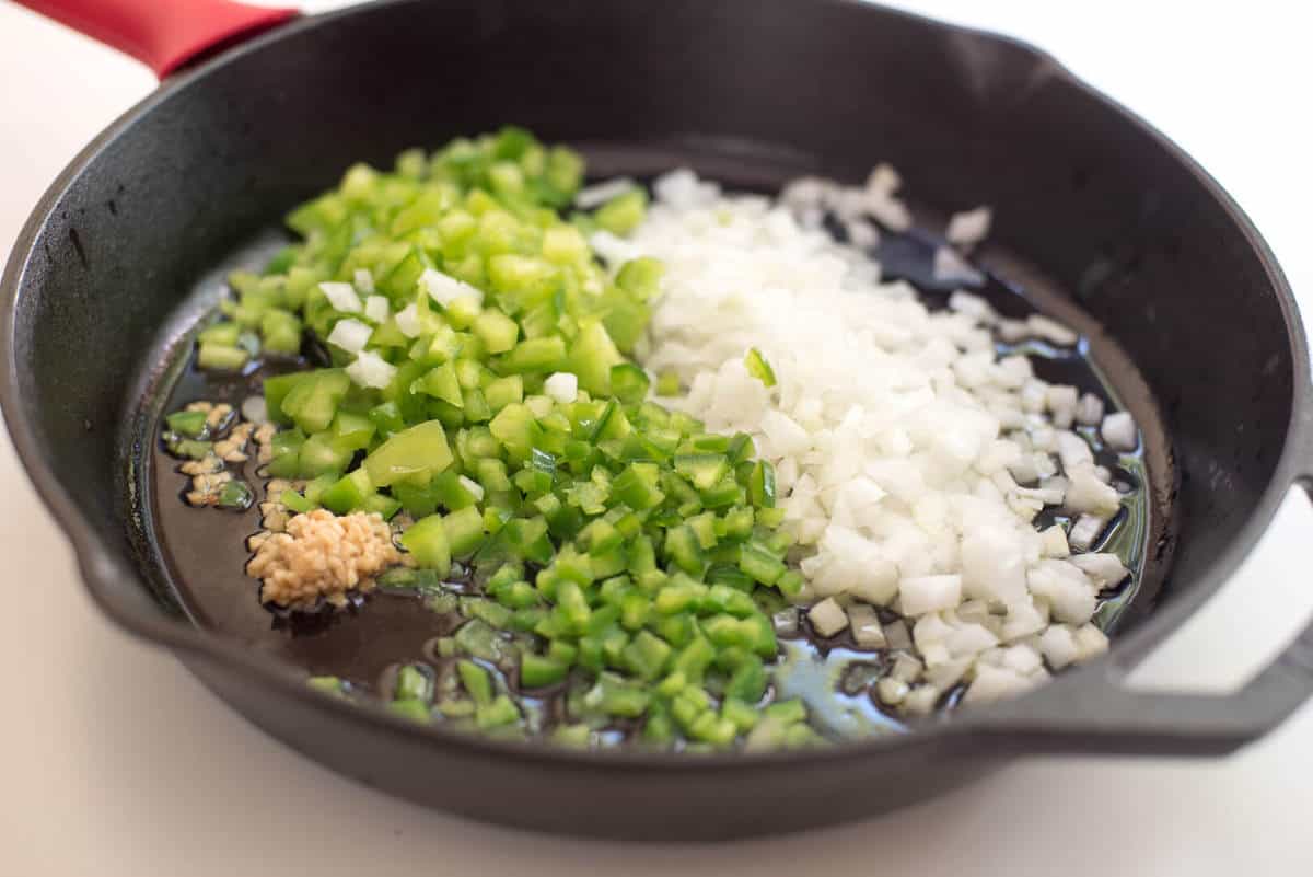 Onion, green bell pepper, and garlic in a cast iron skillet.