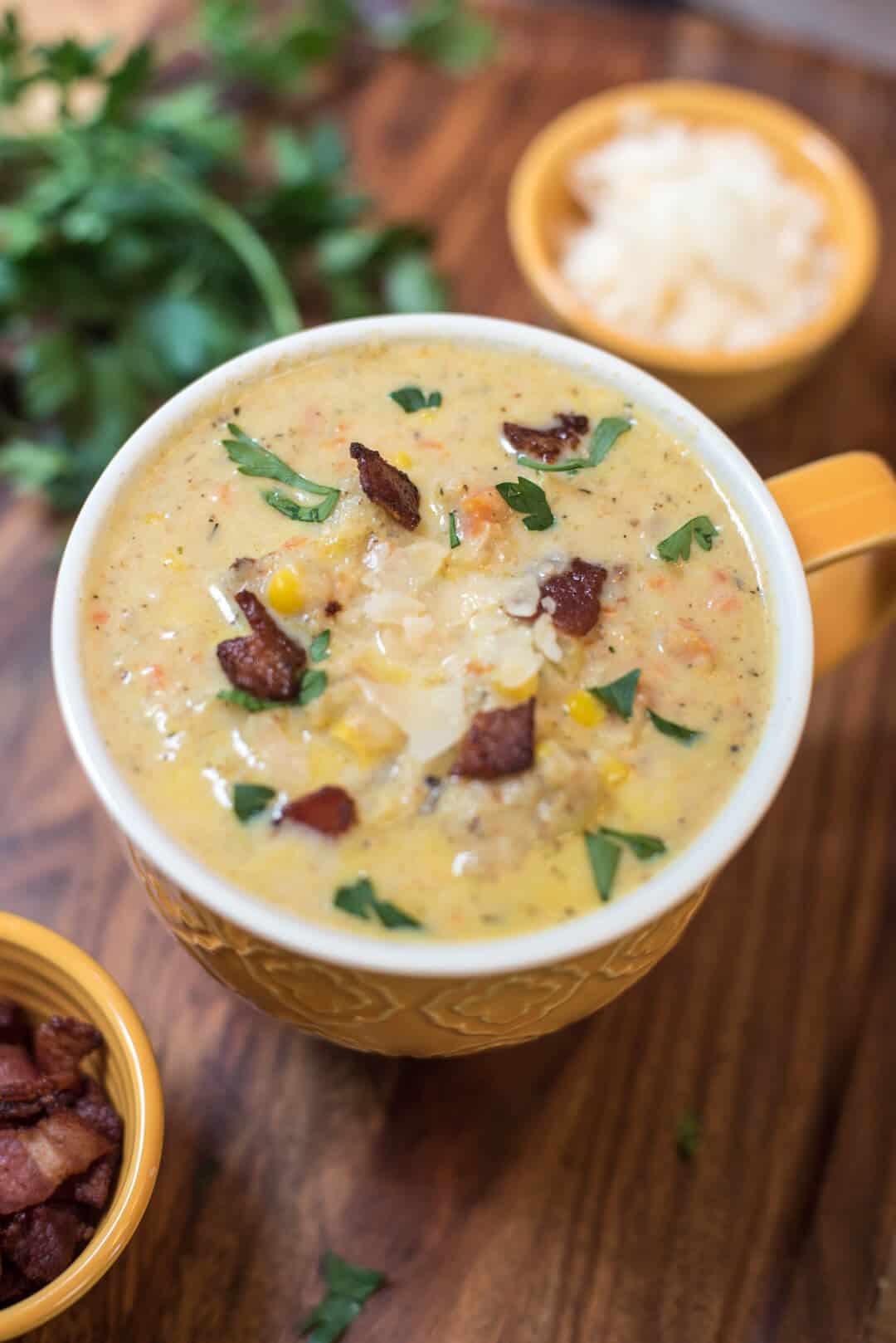 A closeup of a mugs of Roasted Cauliflower Corn Chowder on a board.