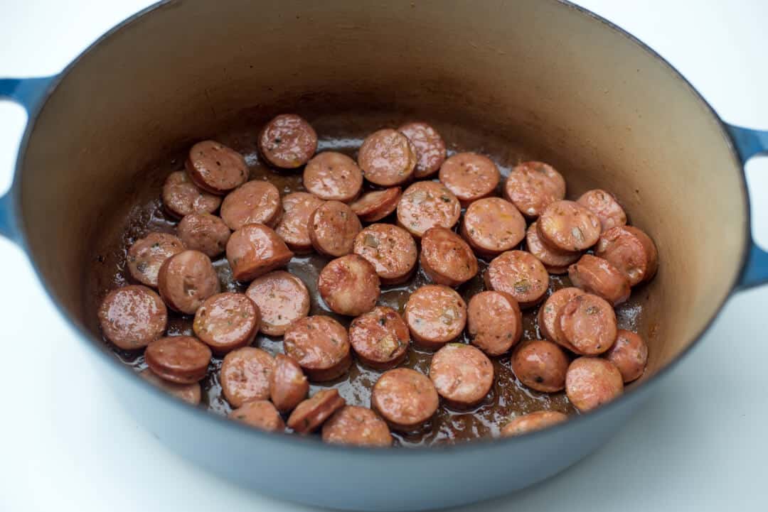Sausage cooking in a Dutch oven.