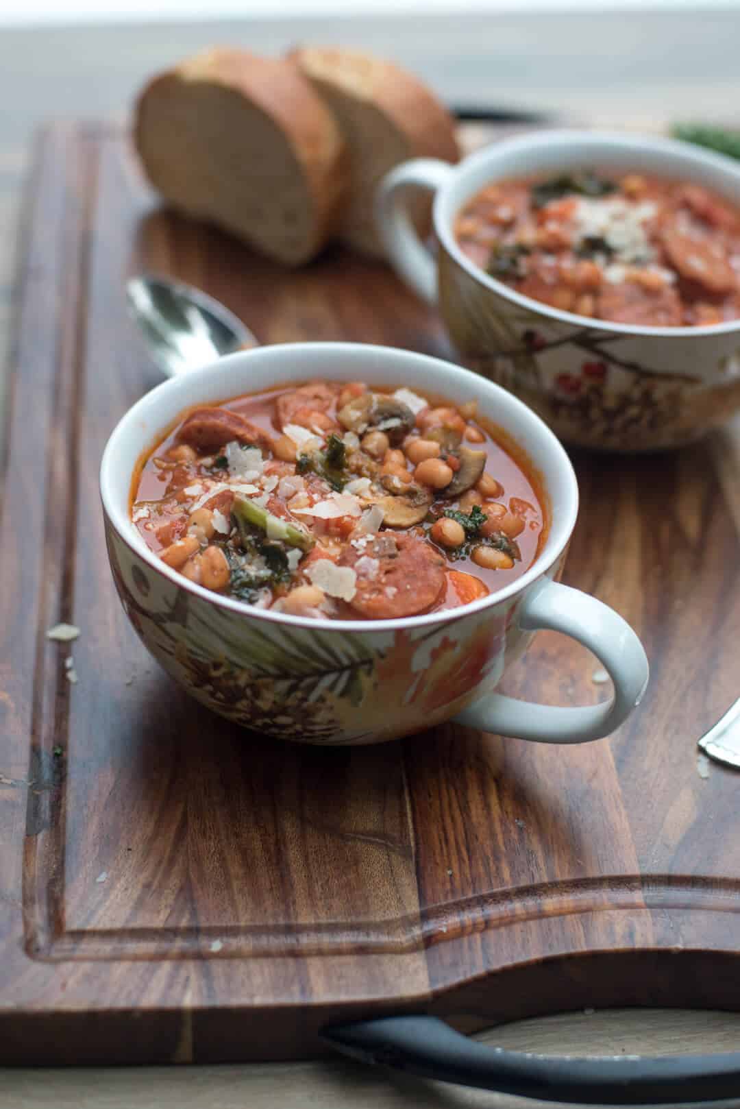 Sausage White Bean and Kale Stew in mugs on a wood board.