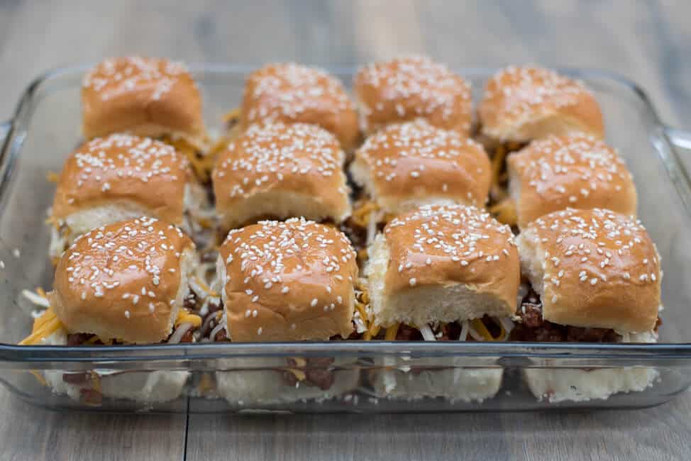 The top half of the buns is placed on top, brushed with melted butter and sprinkled with sesame seeds.