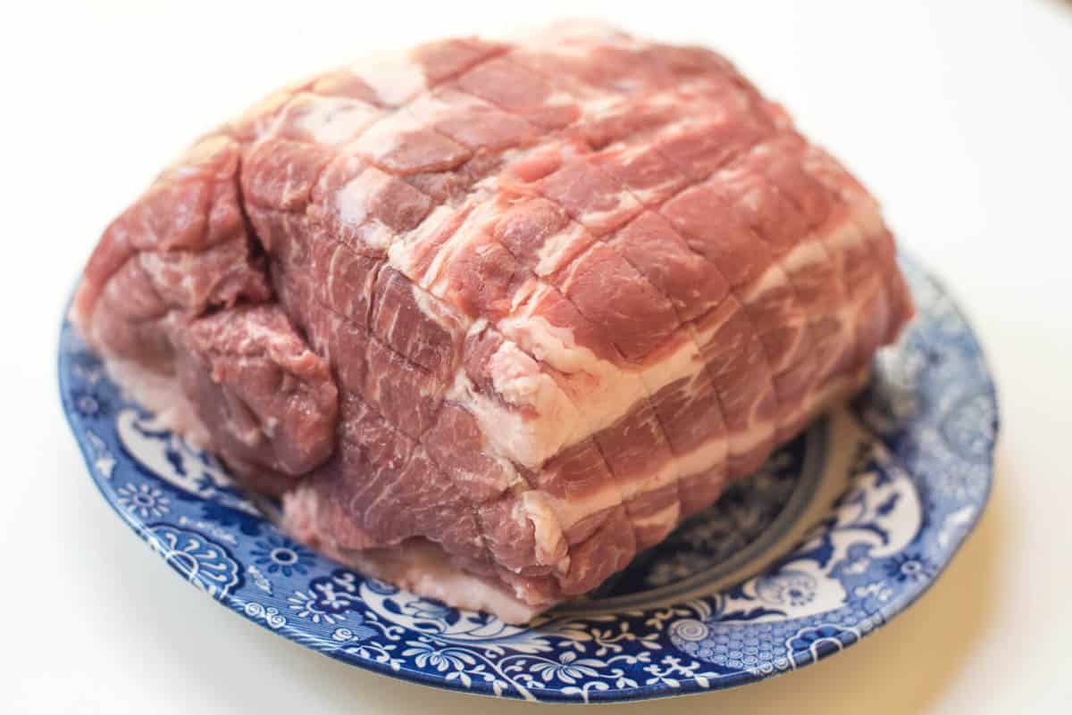 A boneless pork shoulder on a blue and white plate.