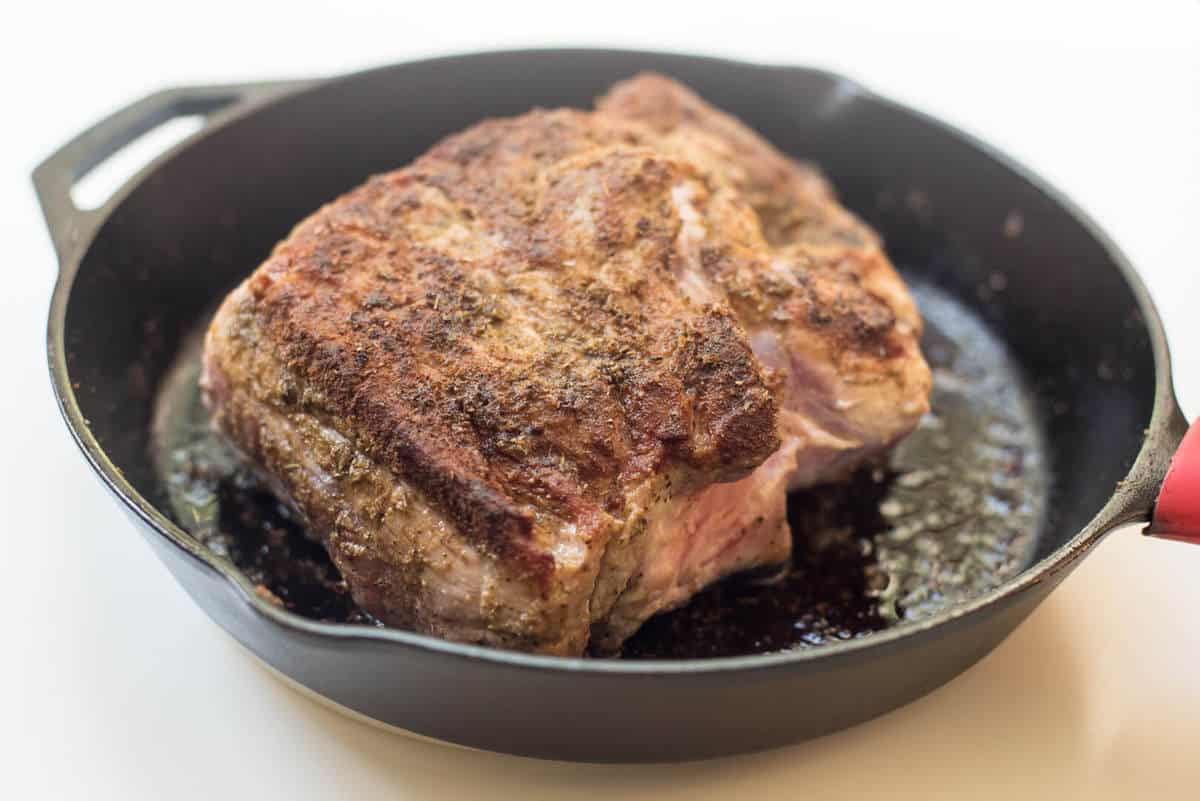 The roast being seared in a cast iron skillet.