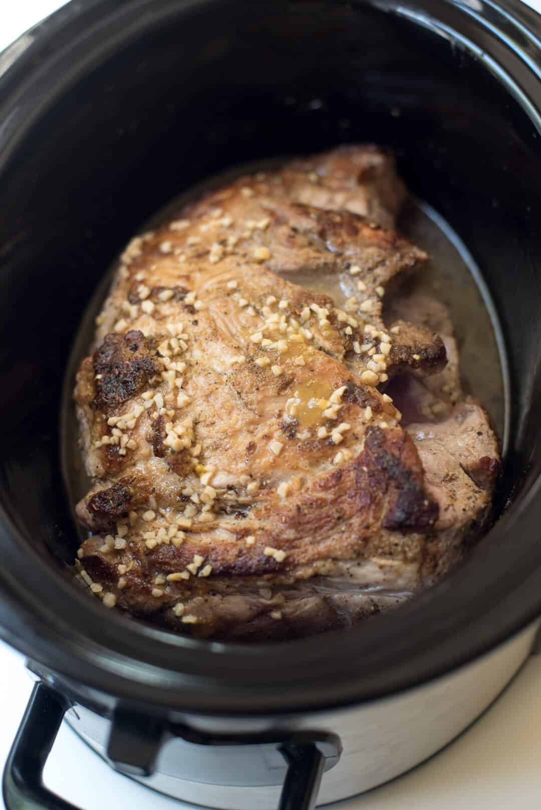 The browned roast in a slow cooker.