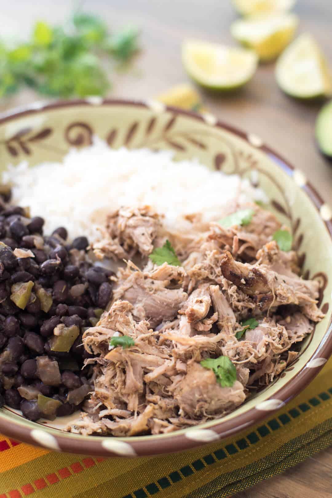 Slow Cooker Cuban Pork with Black Beans and white ice in a patterned bowl.